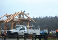 Workers construct a log pavilion