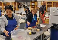 State Sen. Lisa Williams helping students in kitchen.