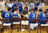 Coach talks to basketball players in a huddle