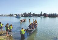 Paddlers in Native American cedar canoes land at the Swinomish Reservation