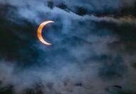 Photo of partial solar eclipse with clouds.