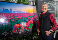 Gary Brown stands next to large tulip festival 2024 poster.