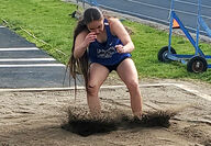 A girl lands the triple jump in the sand